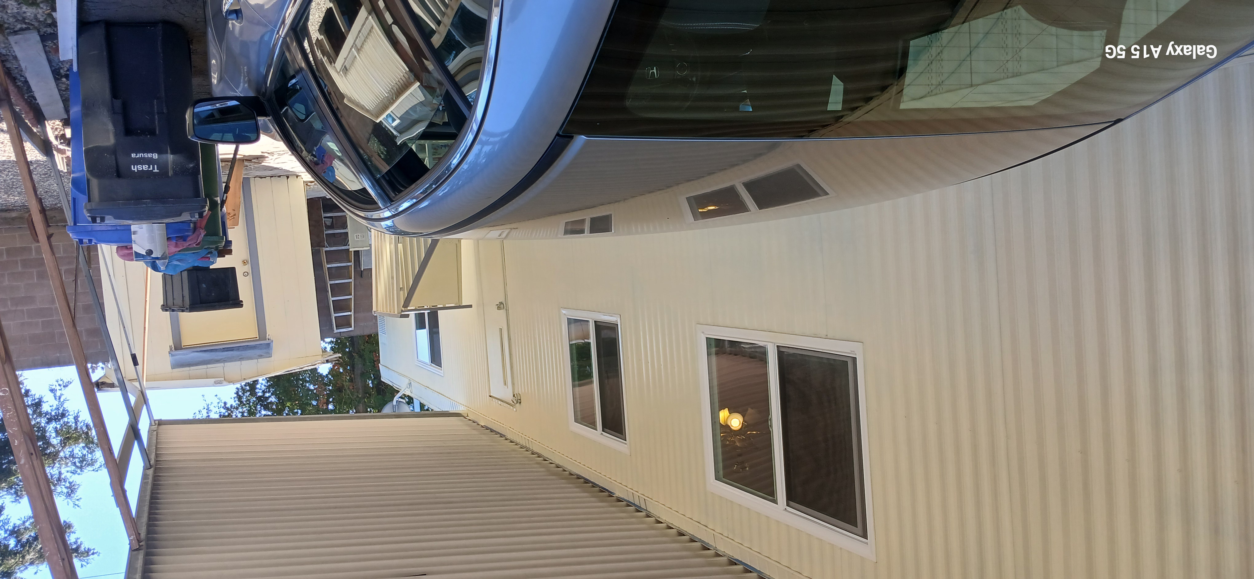 Covered carport alongside the home with a parked car