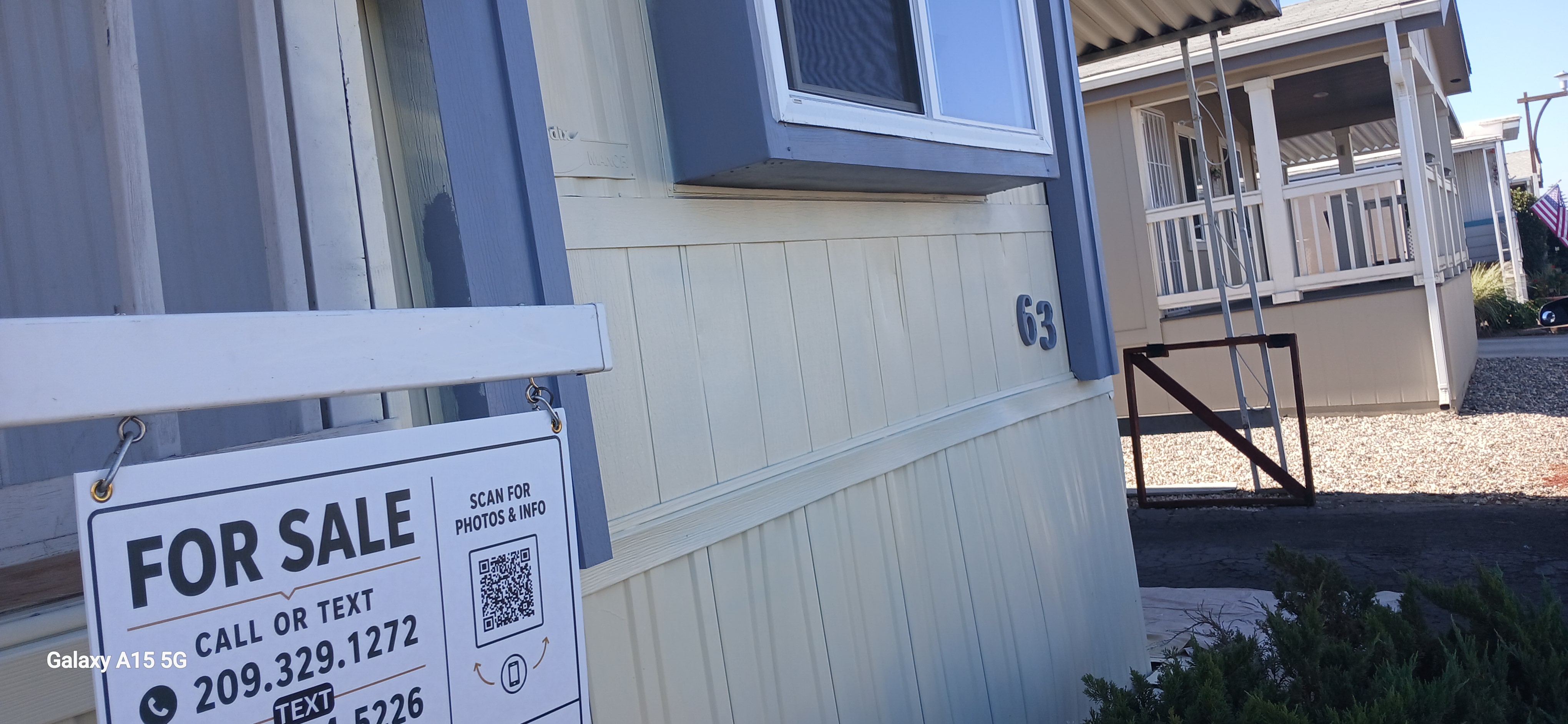 Front exterior with space number 63, the existing yard sign, and shrubs