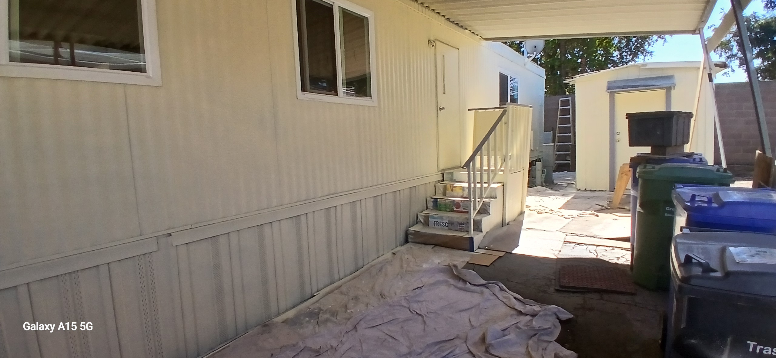 Storage shed behind the home, with side entrance steps and outdoor bins