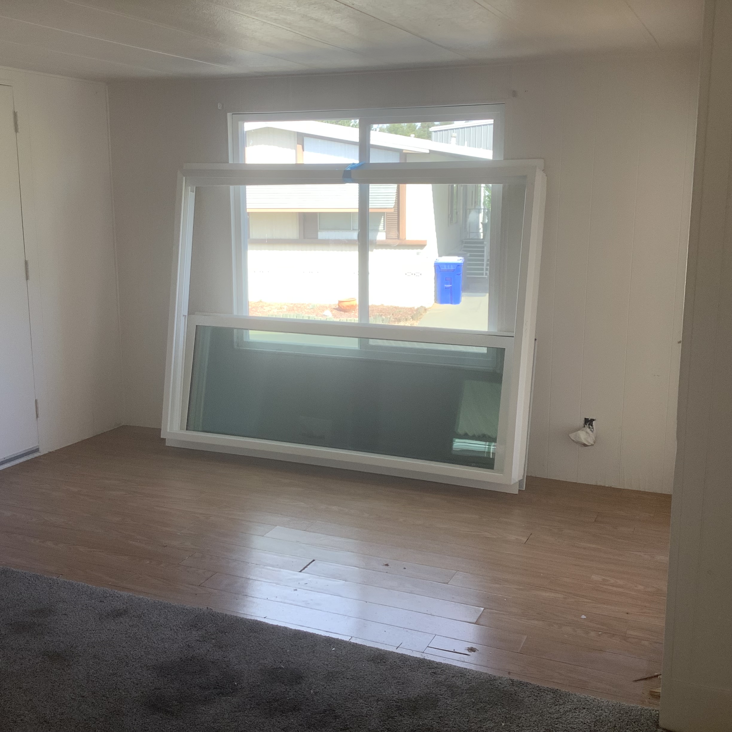 Interior room with wood-look flooring and a window frame leaning against the wall