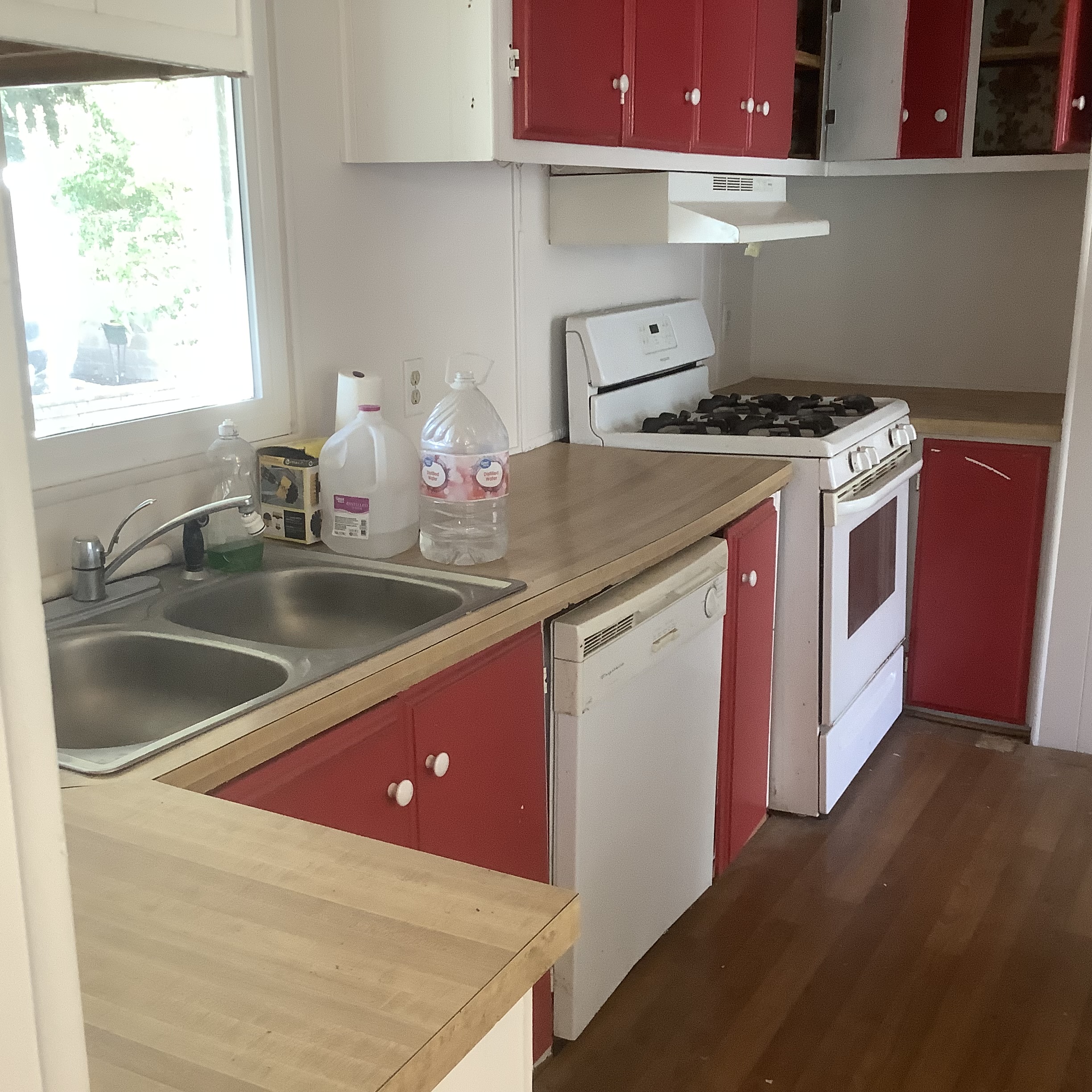 Kitchen with red cabinets, sink, dishwasher, and stove
