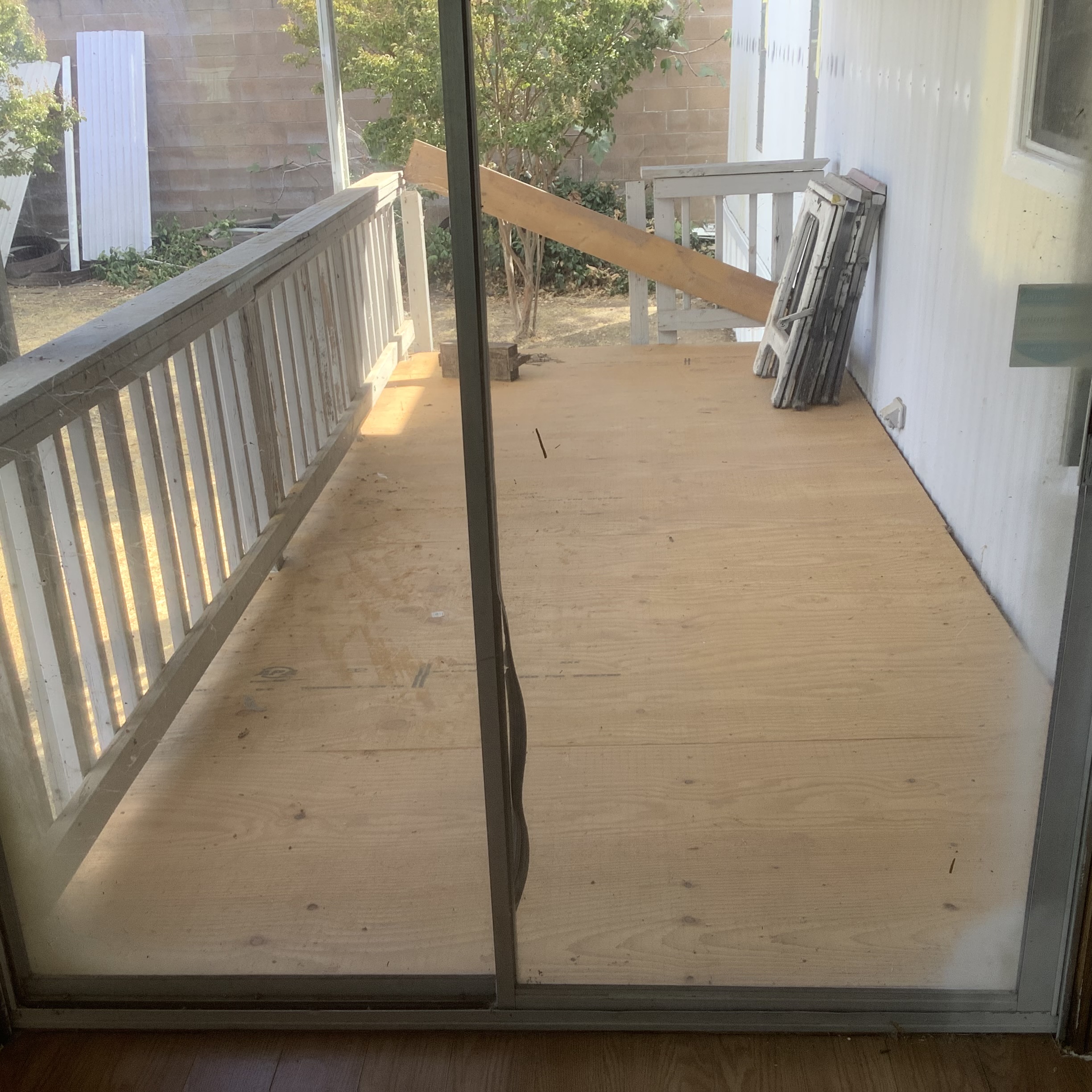 Covered porch with wood railing and a view of the yard